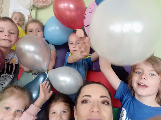 Grupa dzieci z kolorowymi balonami.