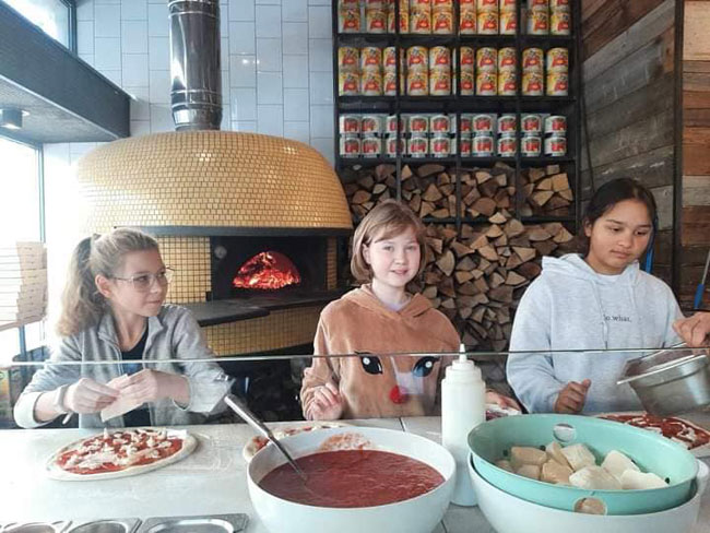 Trzy dziewczynki robiace pizzę.