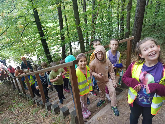 Las - grupa dzieci wchodzaca po drewnianych schodach.