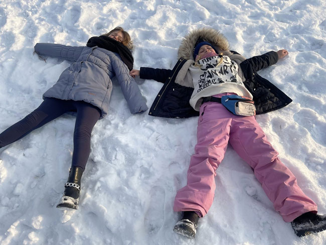 Dwie dziewczynki leżące na śniegu.