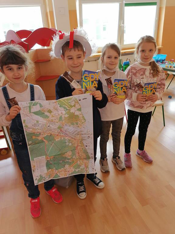 Sala lekcyjna - dwie dziewczynki i dwóch chłopców, chłopcy trzymają mapę.