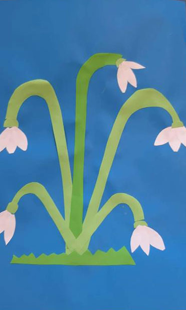 Praca dziecka - niebieskie tło, zielone łodygi, białe kwiatki.