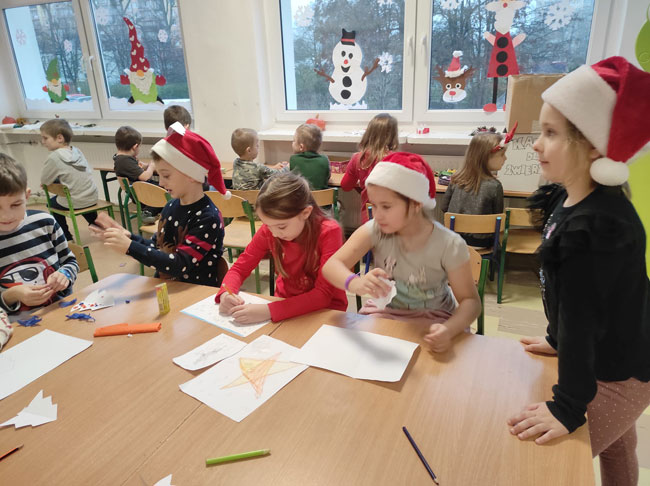 Świetlica - dzieci w czapkach mikołaja, wykonują ozdoby choinkowe.