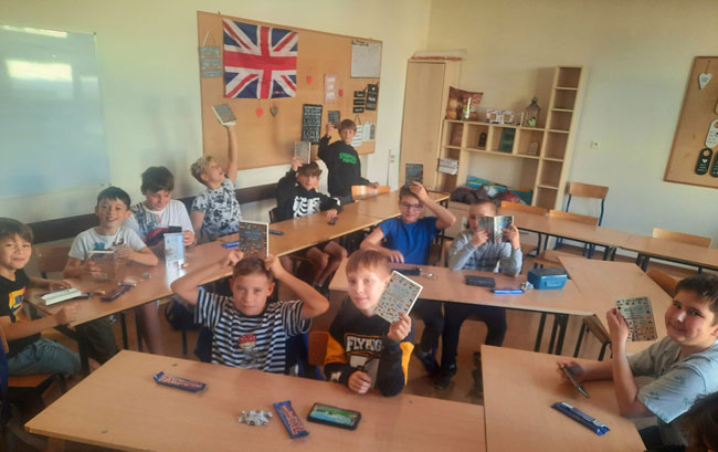 Sala lekcyjna - 11 chłopców z książkami w dłoniach.
