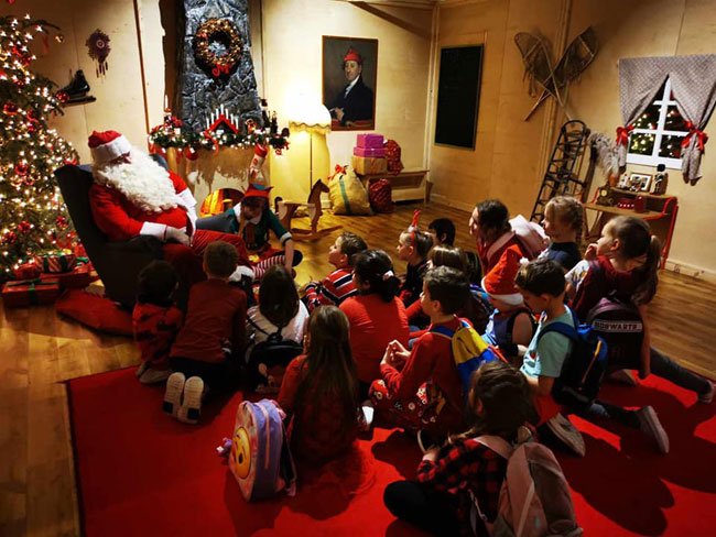 Dzieci siedzące na dywanie, Mikołaj, choinka.